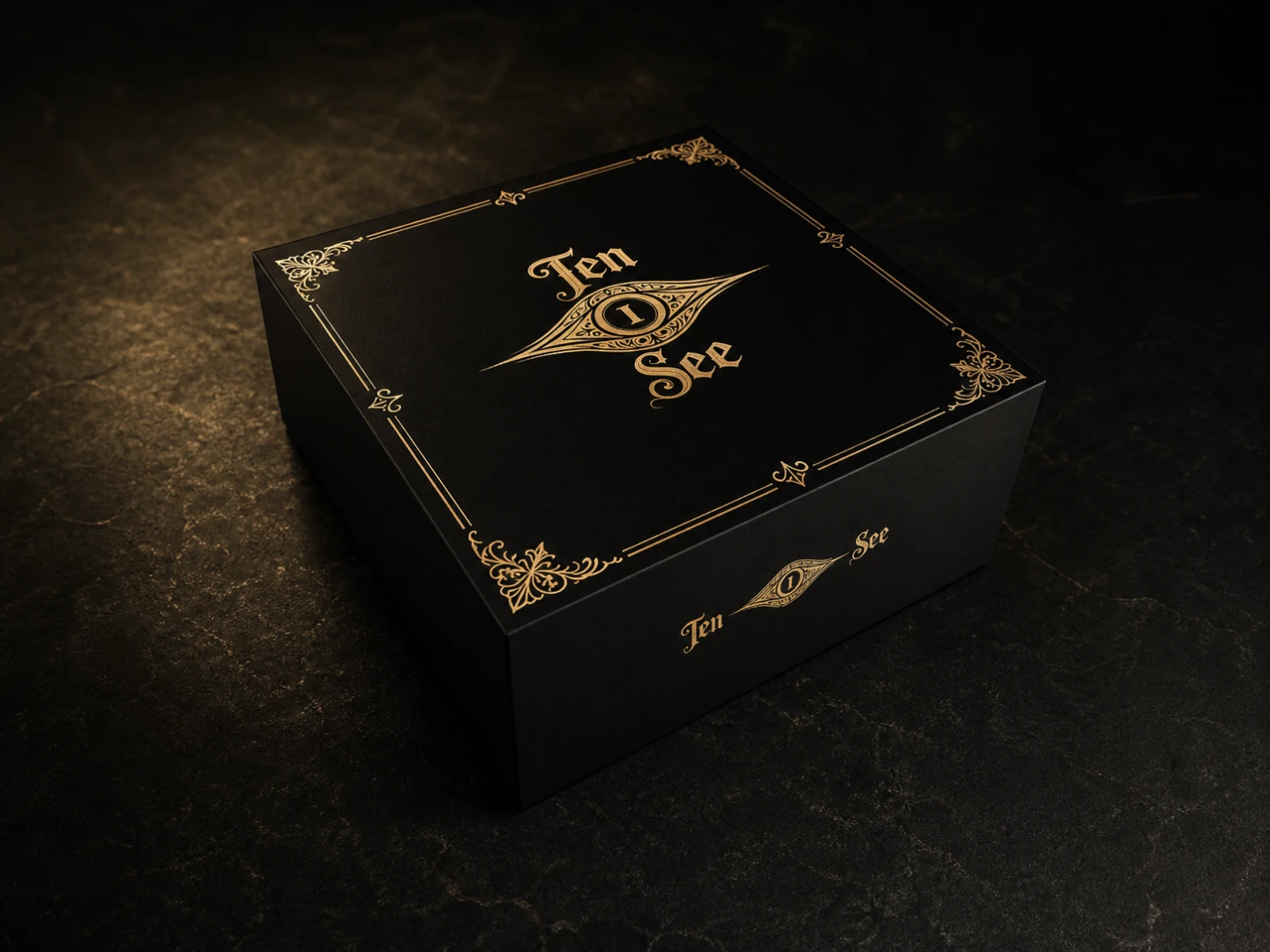 Closed short square TEN I SEE matte-black presentation case with old-gold eye insignia and corner ornaments