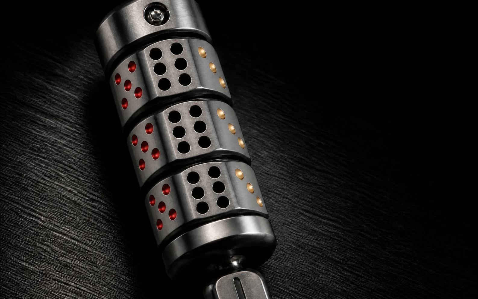 Macro view of ØDDS 777 with five red left dots, six black center holes, and three diagonal gold right dots on each rotating chamber